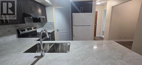 A kitchen with a white counter top and a stainless steel sink.