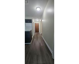 A long hallway with a brown floor and white walls.