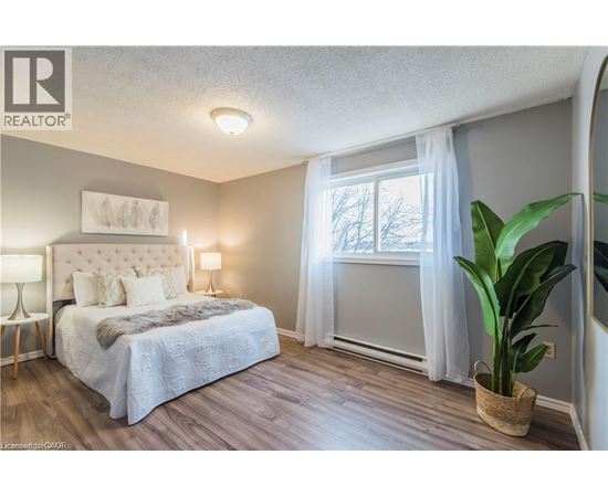 A bedroom with a large bed and a potted plant.