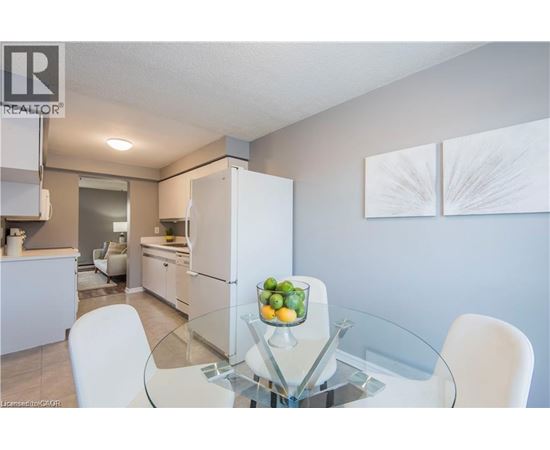 A modern kitchen with a glass table and white chairs.