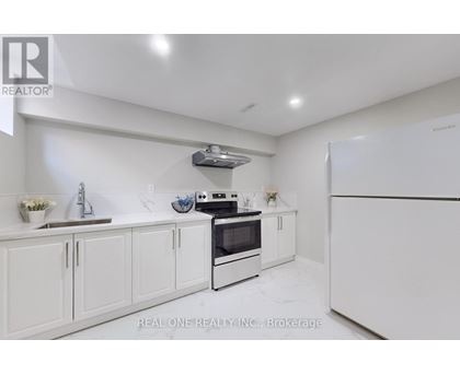 A white kitchen with a refrigerator, oven, and sink.