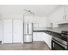 A kitchen with white cabinets and a black countertop.