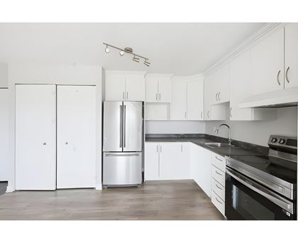 A kitchen with white cabinets and a black countertop.