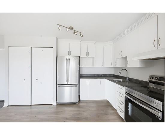 A kitchen with white cabinets and a black countertop.
