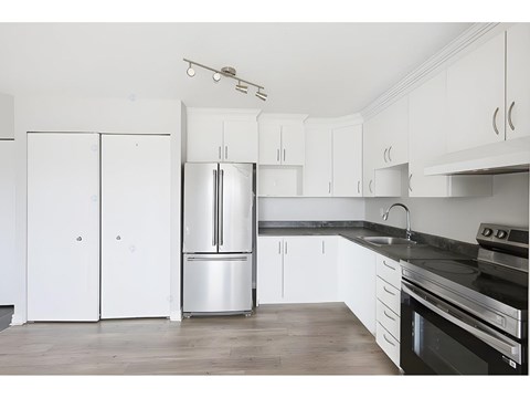 A kitchen with white cabinets and a black countertop.