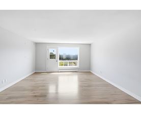 A room with a white door and a window with a view of a street.