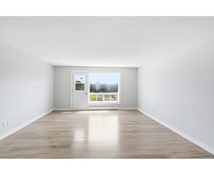 A room with a white door and a window with a view of a street.