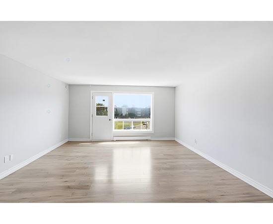 A room with a white door and a window with a view of a street.