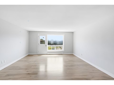 A room with a white door and a window with a view of a street.