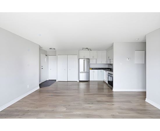 A kitchen with white cabinets and a wooden floor.