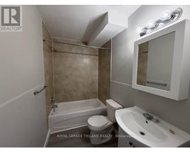 A bathroom with a tub, toilet, and sink.