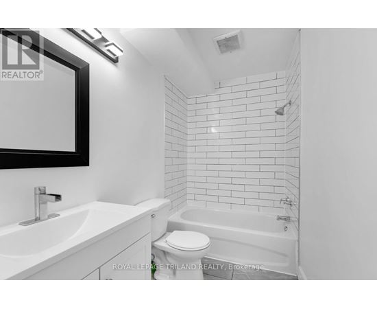 A white bathroom with a tub, sink and toilet.