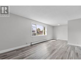 A white room with a window and wooden flooring.