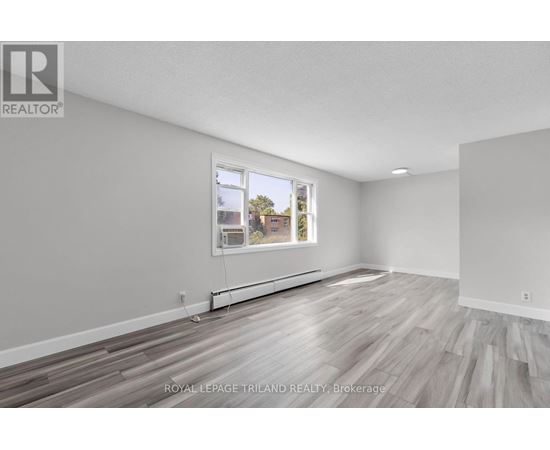 A white room with a window and wooden flooring.