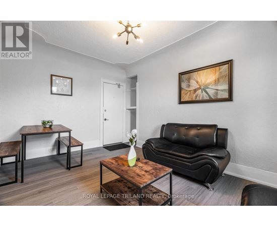 A living room with a black leather couch, a wooden coffee table, and a painting on the wall.