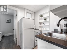 A white refrigerator is in a kitchen with a sink and a counter.