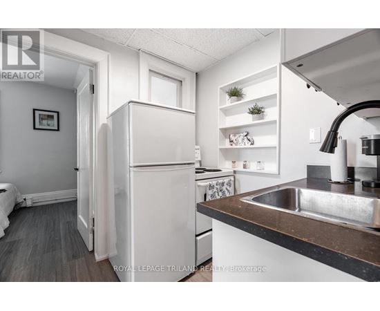 A white refrigerator is in a kitchen with a sink and a counter.