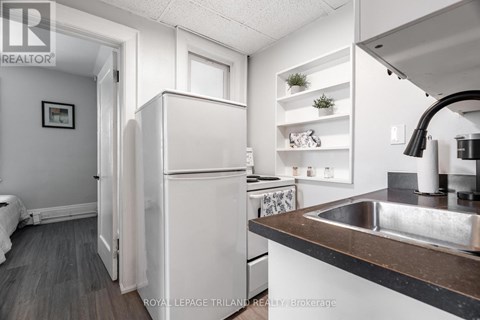 A white refrigerator is in a kitchen with a sink and a counter.