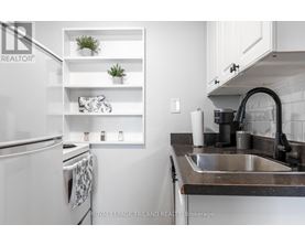 A kitchen with a white refrigerator and a black sink.