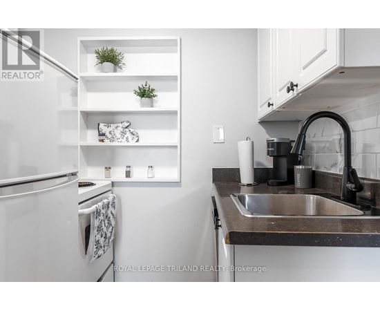 A kitchen with a white refrigerator and a black sink.