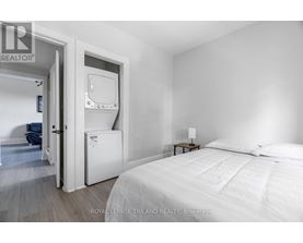 A bedroom with a bed, nightstand, and a small fridge.