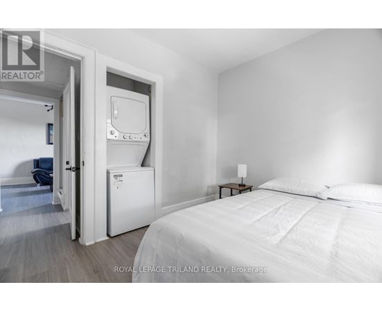 A bedroom with a bed, nightstand, and a small fridge.