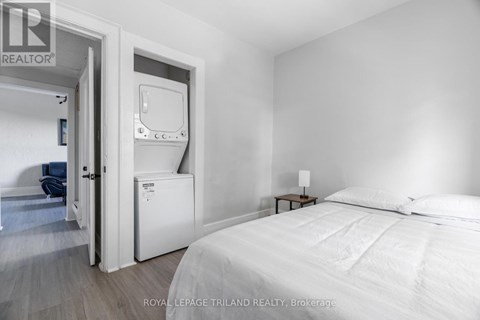 A bedroom with a bed, nightstand, and a small fridge.