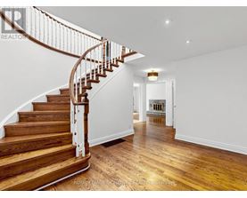 A wooden staircase with a white railing leads to a bright room.