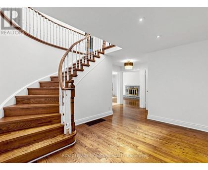 A wooden staircase with a white railing leads to a bright room.