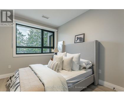 A bedroom with a large bed and a window overlooking trees.