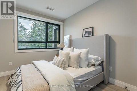 A bedroom with a large bed and a window overlooking trees.
