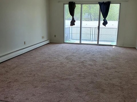 A room with a carpeted floor and a sliding glass door.