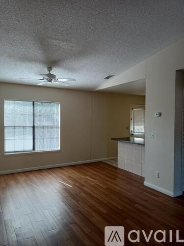 A room with a ceiling fan and wooden flooring.