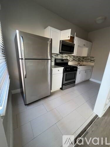 A kitchen with a stainless steel refrigerator, microwave, and oven.