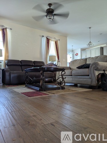 A living room with a black leather sofa and a grey sofa with a wooden floor.
