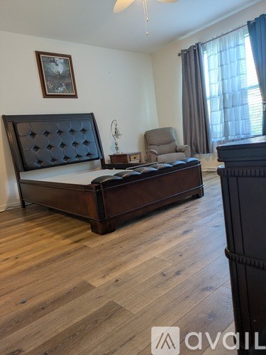 A bedroom with a large bed and a chair.