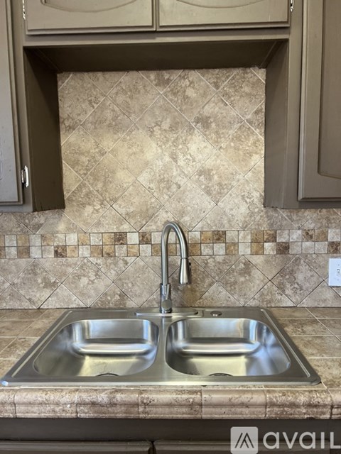 A kitchen with a double sink and brown cabinets.