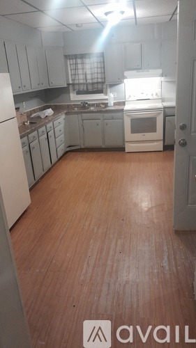 A kitchen with white appliances and wooden floors.