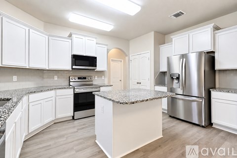 A kitchen with white cabinets and a granite countertop.
