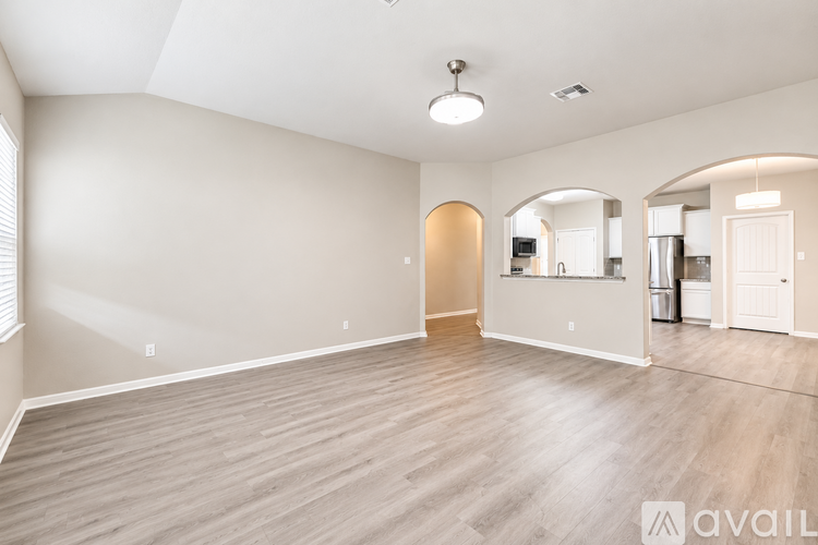 A spacious room with wooden flooring and a large arched doorway.
