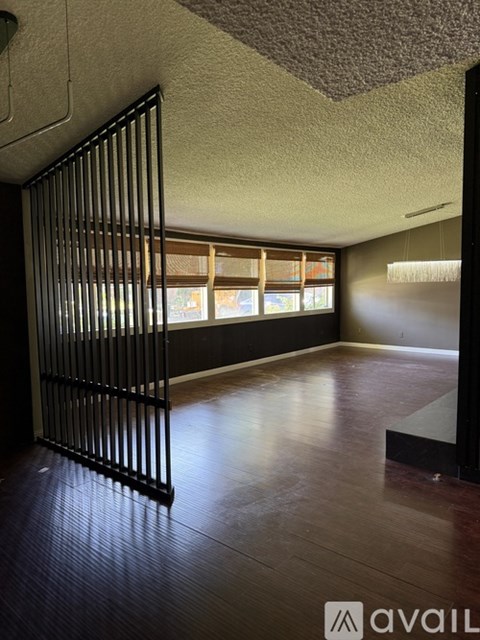 A room with wooden flooring and a door leading to another room.