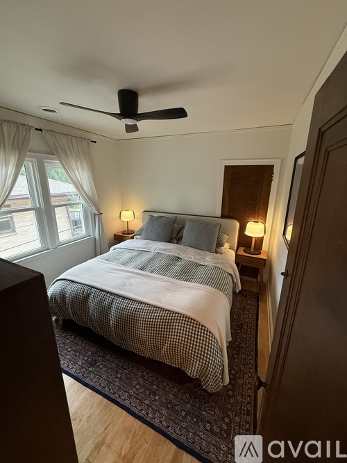 A bedroom with a bed, two lamps, and a ceiling fan.