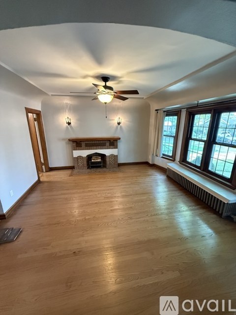 A living room with a fireplace and a ceiling fan.