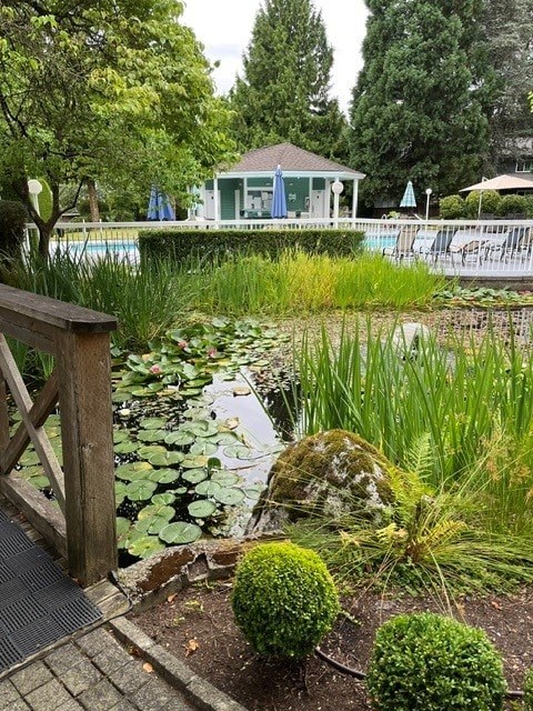 A garden with a wooden bridge and a gazebo in the background.