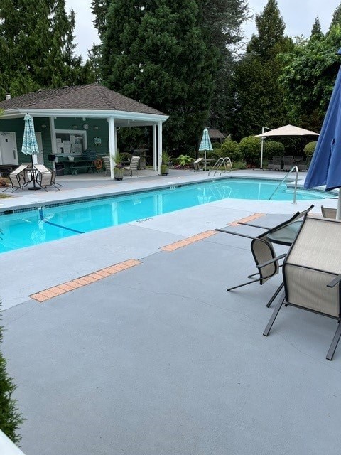 A pool with a blue tiled edge and a white umbrella.