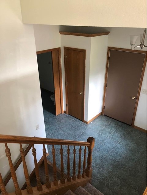A hallway with a staircase and two doors.