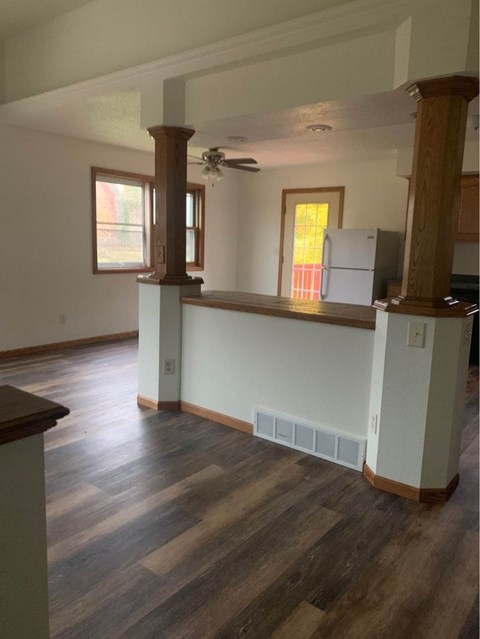 A kitchen with a white refrigerator and wooden floors.