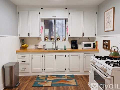A kitchen with white cabinets and a white stove top oven.