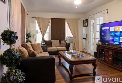 A living room with a brown sofa, a coffee table, and a television displaying various streaming services.