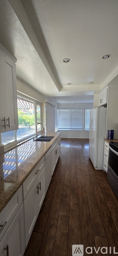 A kitchen with white cabinets and a wooden floor.